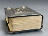 a silver book with a green stone in it