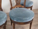 three chairs with blue upholstered cushions are on a wooden floor