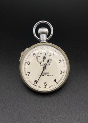 une montre de poche en argent posée sur une surface noire