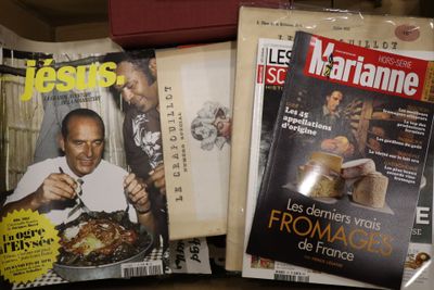 des magazines posés sur une table, devant lesquels se tient un homme tenant un couteau