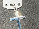 une croix en argent à laquelle est attachée une étiquette