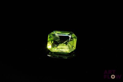 a green diamond on a black surface with a black background