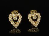 une paire de boucles d'oreilles en diamant en forme de cœur posées sur un fond noir