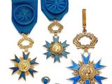 trois médailles et une médaille sont exposées sur un support blanc