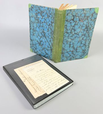 an open book with a blue and green cover next to a notepad