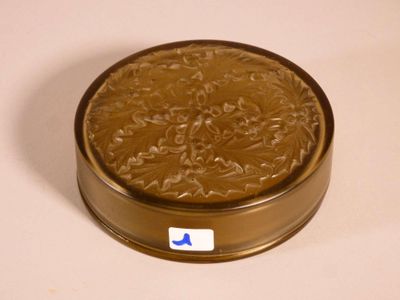 une petite boîte en métal avec un couvercle marron posée sur une surface blanche