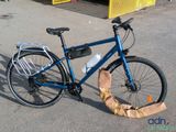 a blue bicycle parked in a parking lot with a bag on the ground