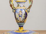 a blue and yellow vase on a stand on a table