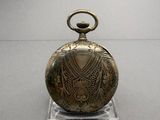 a gold pocket watch on a clear stand on a table