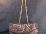 un sac à main en cuir marron auquel est suspendue une chaîne dorée