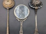 three spoons and a mirror sitting on a table