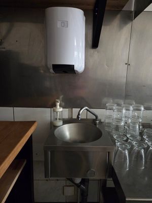 un évier en inox dans une petite cuisine où s'entassent de nombreux verres sur le plan de travail