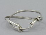 silver bracelet with knot detail on a gray background