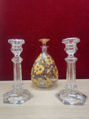 three glass candlesticks on a table with a vase in the background