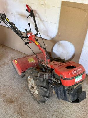 une petite débroussailleuse rouge rangée dans un garage