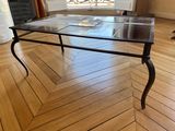une table avec un plateau en verre posée sur un parquet