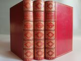 three red books with gold trims are stacked on top of each other