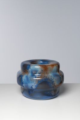 un vase bleu et marron posé sur une table blanche