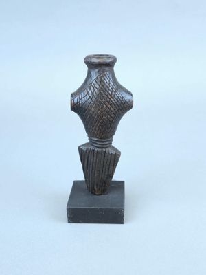 une petite statue représentant un vase posée sur un petit socle
