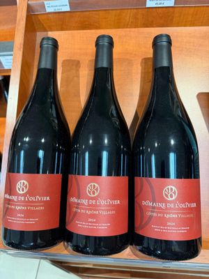 trois bouteilles de vin rouge sont posées sur une étagère dans un magasin