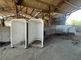 two white toilets in a building with a roof