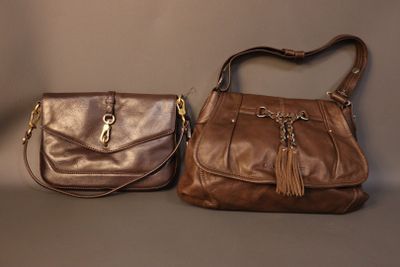 pair of brown leather handbags with tassels on a grey background