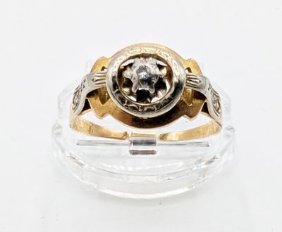 une bague sertie d'un diamant, posée sur une surface transparente