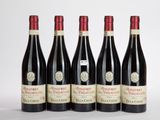 quatre bouteilles de vin sont alignées sur une surface blanche