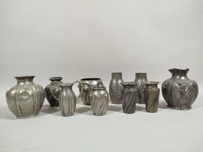 several silver vases are lined up in a row on a white surface