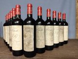 six bottles of red wine lined up on a wooden table
