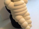 une petite figurine blanche représentant un personnage de dessin animé assis sur un pneu