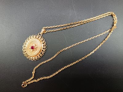 un gros plan d'un collier en or orné d'une pierre rouge