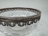 a glass bowl with a silver rim on a white surface