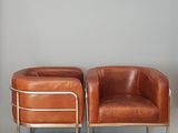 deux fauteuils en cuir marron placés l'un à côté de l'autre sur un sol blanc