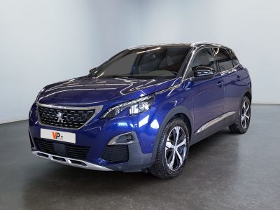 La voiture bleue est garée dans une grande pièce au sol noir.