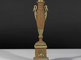 un vase antique en bronze posé sur un socle, sur fond noir