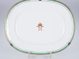une assiette blanche bordée de vert et ornée d'une couronne dorée