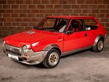 a red car that is parked in front of a brick wall