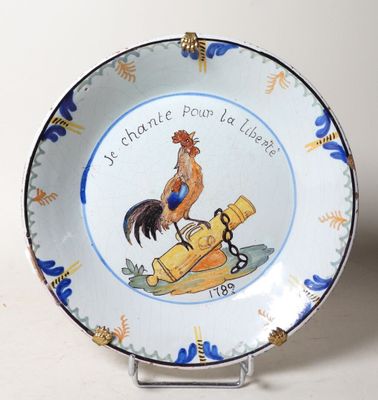 une assiette ornée d'un coq, posée sur un socle