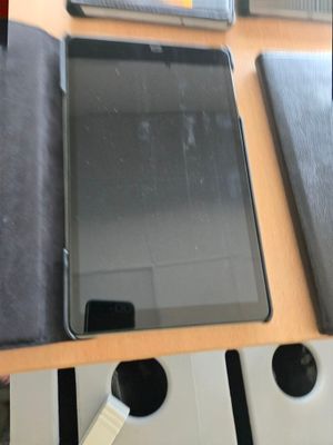une tablette posée sur un bureau, à côté d'un ordinateur portable