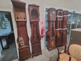 many wooden grandfather clocks on display in a room