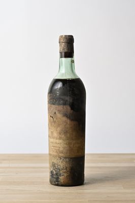 an old bottle of wine sitting on top of a wooden table