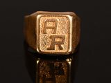 a close up of a gold signet ring on a black surface