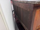 a wooden cabinet with a marble top in a kitchen