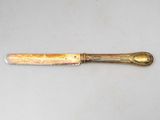 an image of a knife with a gold handle on a white surface