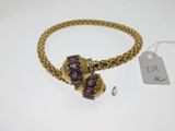 un gros plan d'un bracelet en or orné de pierres violettes