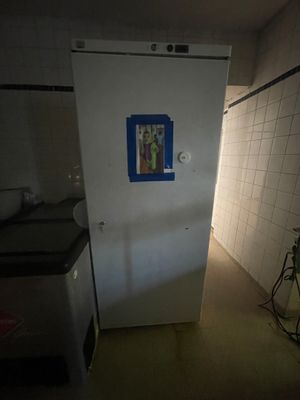 un réfrigérateur blanc dans une pièce sombre, avec une porte bleue