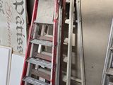 Plusieurs échelles sont alignées contre un mur dans un garage.