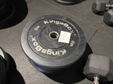 une photo montrant une plaque de poids et des haltères posés sur le sol d'une salle de sport