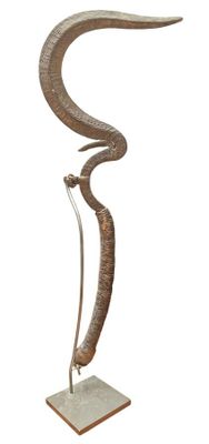 une photo d'une sculpture métallique représentant un serpent, posée sur un socle